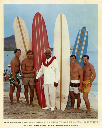 Duke Kahanamoku with the officers of the world famous Duke Kahanamoku Surf Club; International Marketplace, Waikīkī beach. (Left to Right)Paul Strauch, Jr., Joey Cabell, The Duke, Fred Hemmings, Butch Van Artsdalen. Collection: Kahanamoku Collection Call Number: Kahanamoku. Recreation. Sports. Surfing. Location: Bishop Museum Archives Image from Bishop Museum Archives, Honolulu, Hawaii. Images are not to be re-used without permission.