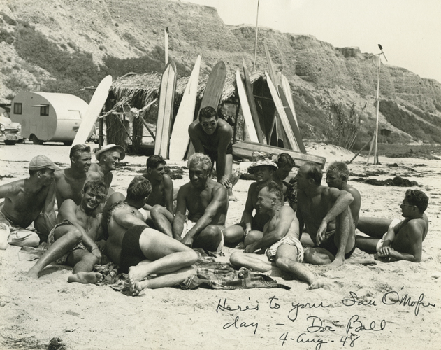 Duke Kahanamoku with the San Onofre Surf Club; San Clemente, California. (Left to right, front) James "Burrhead" Drever, John Kernin, Doc Ball. (Left to right, seated)Obie Rod, Gordon Freeman, Ed "Pop" Proctor, "Viking", Duke Kahanamoku, Barney Wilkes (standing behind Kahanamoku), "Whitey" Harrison, unknown, unknown, Bob "Hammerhead" Gravage, Fritz Watson (seated behind and to the right of "Hammerhead"), John Droege (reclined, far right). Collection: Kahanamoku Collection Call Number: Kahanamoku. Recreation. Sports. Surfing. Location: Bishop Museum Archives Image from Bishop Museum Archives, Honolulu, Hawaii. Images are not to be re-used without permission.