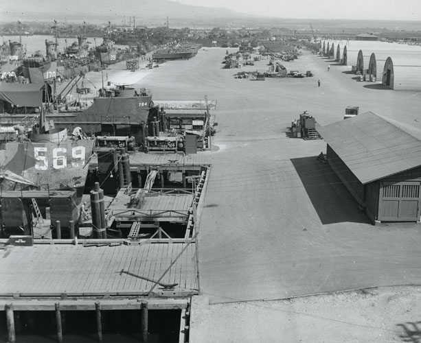 Typical of the rushed construction of the war period, the Waipi‘o Amphibious Naval Base was constructed at very high speed. In less than one year, this site went from having no structures at all, to this functioning facility. The base was used to dock and load landing craft like the ones shown here on the left, which were utilized when American troops were sent ashore in different Pacific locations to fight the Japanese for control of the many islands they had occupied. Call Number: 1975.113, folder 15 Artifact Number: CP_121958 Location: Bishop Museum Archives Image from Bishop Museum Archives, Honolulu, Hawaii. Images are not to be re-used without permission.